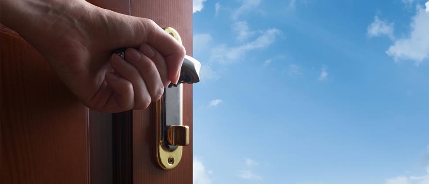 Hand opening door displaying a blue sky beyond the door